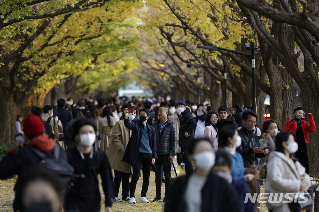 [도쿄=AP/뉴시스] 지난 28일 일본 도쿄에서 신종 코로나바이러스 감염증(코로나19) 감염 예방을 위해 마스크를 착용한 시민들이 노랗게 물든 은행 나무 거리를 걷고 있다. 2020.11.30.