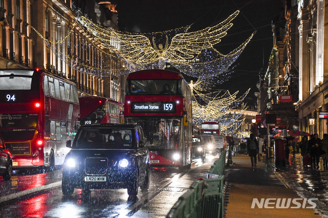 [런던=AP/뉴시스]3일(현지시간) 영국 런던의 리젠트 거리의 크리스마스 장식 밑으로 버스와 택시들이 지나고 있다. 영국의 코로나19 일일 사망자가 414명 늘어 누적 사망자가 6만 명(6만113명)을 넘기며 유럽에서는 처음이자 전 세계에서는 미국, 브라질, 인도, 멕시코에 이어 5번째를 기록하게 됐다. 2020.12.04. 
