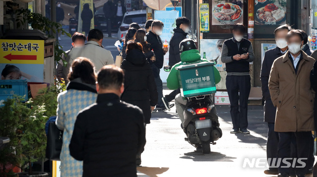 [서울=뉴시스] 고범준 기자 = 신종 코로나바이러스 감염증(코로나19) 사태로 도시락 점심이 늘고 있는 8일 오후 서울 중구 무교로 일대에서 직장인들 사이로 배달 오토바이가 달리고 있다. 2020.12.08. bjko@newsis.com