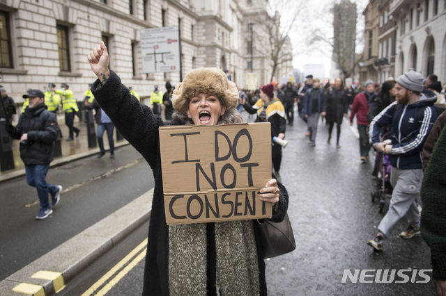 [런던=AP/뉴시스]지난 14일(현지시간) 영국 런던의 웨스트민스터에서 코로나19 백신과 폐쇄에 반대하는 시위가 열려 한 여성이 팻말을 들고 구호를 외치고 있다. 2020.12.23