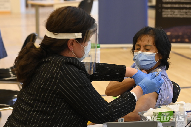 [토론토=AP/뉴시스]14일(현지시간) 캐나다 토론토에서 한 요양보호사가 첫 번째로 코로나19 백신을 접종받고 있다. 2020.12.14.