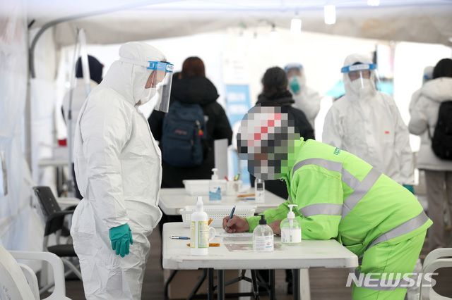 [서울=뉴시스]김선웅 기자 = 869명의 신규 코로나19 확진자가 발생한 22일 서울 성북구청 앞에 설치된 코로나19 임시 선별진료소에서 내방한 시민이 문진표를 작성하고 있다. 2020.12.22. mangusta@newsis.com