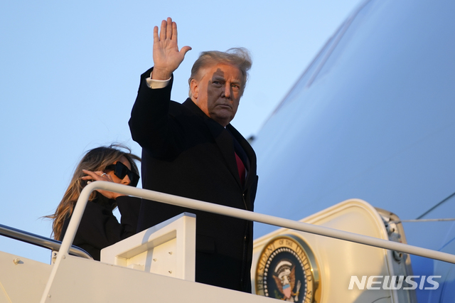 [메릴랜드=AP/뉴시스] 23일(현지시간) 도널드 트럼프 미국 대통령이 메릴랜드주에 있는 앤드루스 공군 기지에서 전용기 에어포스원에 탑승하면서 손을 흔들고 있다. 왼쪽은 영부인 멜라니아 여사. 2020.12.24.
