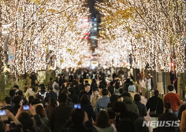 [도쿄=AP/뉴시스]크리스마스 전날인 24일 일본 도쿄의 한 거리에서 시민들이 나무에 장식된 조명을 휴대폰으로 촬영하고 있다. 2020.12.24.