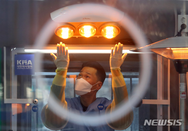 [서울=뉴시스]배훈식 기자 = 전국 곳곳에 한파 특보가 내려진 30일 오전 서울 중구 서울시청 광장에 설치된 신종 코로나바이러스 감염증(코로나19) 임시 선별검사소에서 한 의료진이 언 손을 온열기에 녹이고 있다. 2020.12.30. dahora83@newsis.com