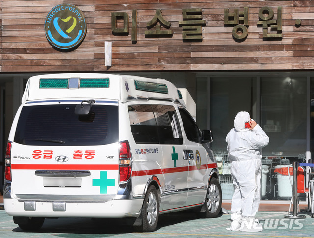 [서울=뉴시스] 박미소 기자 = 30일 오후 서울 구로구 미소들요양병원에서 방호복을 입은 관계자가 구급차 앞에서 통화를 하고 있다. 현재까지 동일집단(코호트) 격리 중인 미소들요양병원의 확진자 180명 중 143명, 비확진자 246명이 다른 병원으로 옮겨졌다. 현재 요양병원에 남은 인원은 총 129명이다.2020.12.30. misocamera@newsis.com