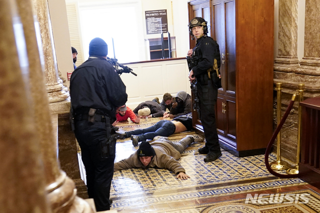 [워싱턴=AP/뉴시스]6일(현지시간) 미 의회 경비대가 의사당에 난입한 도널드 트럼프 대통령 지지자들을 하원 근처에서 총으로 제압하고 있다. 2021.01.07.