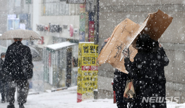 [서울=뉴시스]박주성 기자 = 수도권을 포함한 중부지방에 눈이 내리기 시작한 지난 12일 오후 서울 서초구 인근에서 시민들이 상자를 쓰고 걸어가고 있다. 2021.01.12. park7691@newsis.com