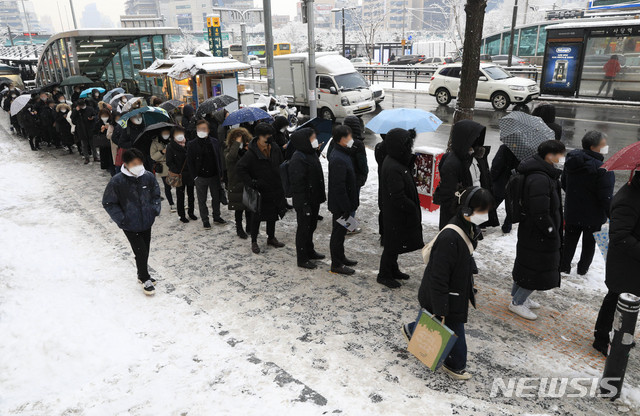 [서울=뉴시스] 박민석 기자 = 서울 지역에 눈이 내리고 있는 12일 오후 서울 동작구 사당역 인근에서 시민들이 버스를 탑승하기 위해 길게 줄을 서 있다. 2021.01.12. mspark@newsis.com