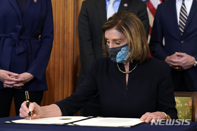 [워싱턴=AP/뉴시스]낸시 펠로시 미 하원의장이 13일(현지시간) 의회에서 도널드 트럼프 대통령의 탄핵소추안에 서명하고 있다. 펠로시 의장은 "오늘 하원은 그 누구도 법 위에 있지 않다는 것을 증명했다"라고 하원의 탄핵소추안 가결을 평가했다. 2021.01.14.