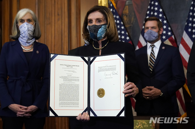 [워싱턴=AP/뉴시스]미국 민주당 낸시 펠로시 하원의장이 13일(현지시간) 의회에서 도널드 트럼프 대통령 탄핵소추안에 서명해 들어 보이고 있다. 2021.01.14. 
