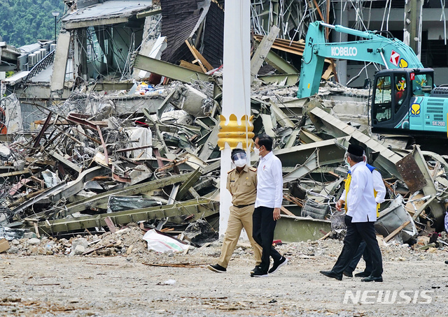 [마무주=AP/뉴시스]인도네시아 대통령궁이 공개한 사진에 조코 위도도(가운데) 대통령이 19일 인도네시아 웨스트 술라웨시주 마무주 지진으로 피해를 입은 정부 청사를 살펴보면서 현지 관계자와 얘기하고 있다. 위도도 대통령은 지진 피해지역을 방문해 피해 주민들을 위로하고 신속한 복구를 지시하는 등 민심을 달랬다. 이번 지진으로 84명이 숨지고, 900여 명이 다쳤으며 약 2만 명의 이재민이 발생했다. 2021.01.19. 