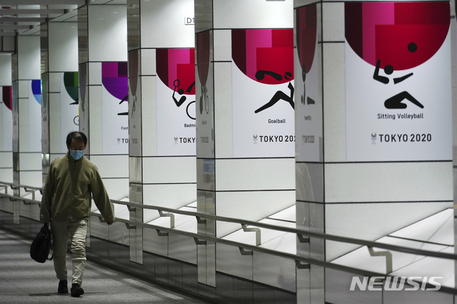 [도쿄=AP/뉴시스]19일 코로나19 예방을 위해 마스크를 쓴 한 남성이 일본 도쿄에서 2020 도쿄올림픽 현수막 근처를 걷고 있다. 도쿄에서는 이날 1240명의 코로나19 신규 확진자가 보고됐다. 2021.01.19. 