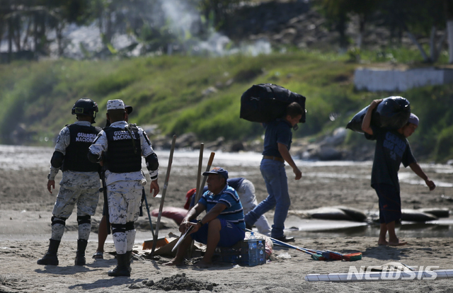 [치우다드 이달고(멕시코)=AP/뉴시스]멕시코의 국경수비대원들이 1월 19일(현지시간) 과테말라 국경을 넘어온 이민들을 붙잡아 수키아테강 부근 이민초소에 인계하고 있다.  