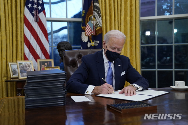 [워싱턴=AP/뉴시스]조 바이든 미국 대통령이 20일(현지시간) 백악관 오벌오피스에서 첫 행정명령에 서명하고 있다. 바이든 대통령은 이날 백악관 입성 이후 연방 부지에서 마스크 착용을 의무화하는 첫 행정명령에 서명했다. 2021.1.20. 