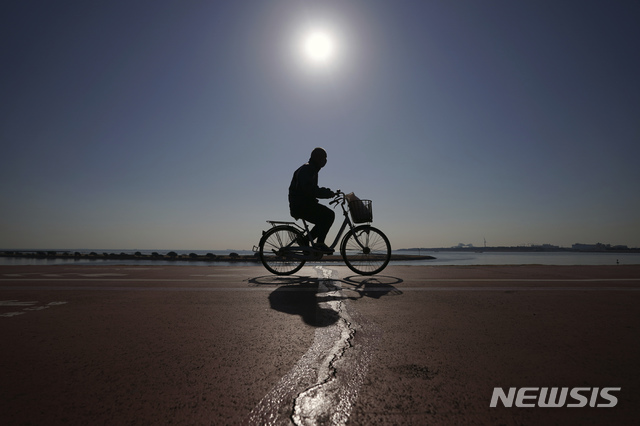 [도쿄=AP/뉴시스]21일 일본 도쿄에서 코로나19 예방을 위해 마스크를 쓴 한 남성이 자전거를 타고 지나가고 있다. 도쿄에서는 이날 1400명 이상의 코로나19 신규 확진자가 보고됐다. 2021.01.21. 
