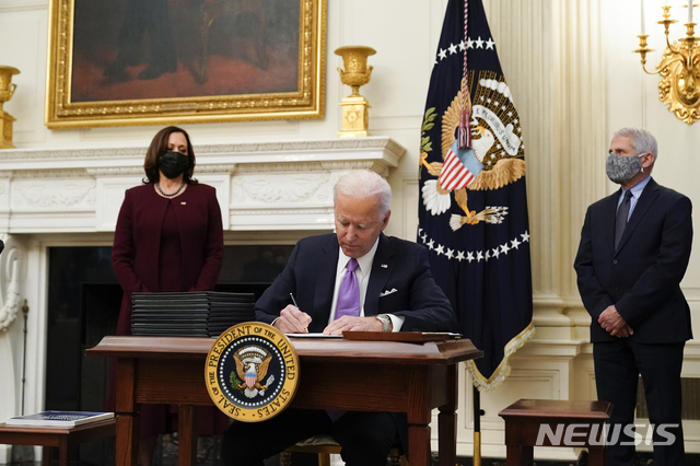 [워싱턴=AP/뉴시스]조 바이든 미국 대통령이 21일(현지시간) 백악관 스테이트 다이닝룸에서 카말라 해리스 부통령과 앤서니 파우치 국립알레르기·전염병연구소 소장이 배석한 가운데 코로나19 관련 행정명령에 서명하고 있다. 2021.01.22.