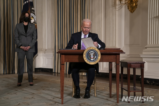 [워싱턴=AP/뉴시스]조 바이든 미 대통령이 26일(현지시간) 백악관에서 카멀라 해리스 부통령이 지켜보는 가운데 미국의 인종 형평성 문제에 대한 행정명령에 서명하고 있다. 2021.1.27