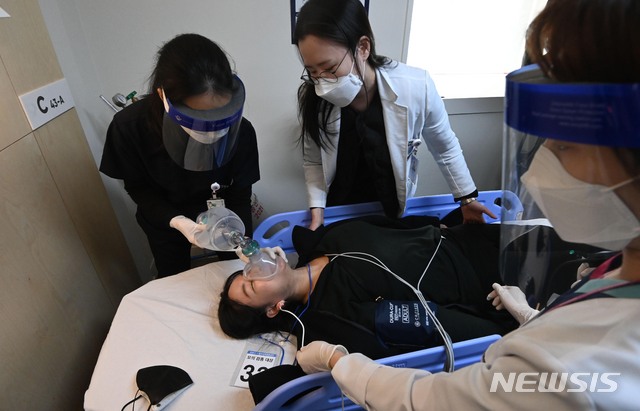 [서울=뉴시스]사진공동취재단 = 9일 오후 서울 중구 국립중앙의료원 중앙예방접종센터에서 열린 코로나19 백신 접종 모의 훈련에서 의료진들이 접종을 마친 후 이상반응을 보인 참가자를 응급처치 후 구급차로 옮기고 있다. 2021.02.09. photo@newsis.com