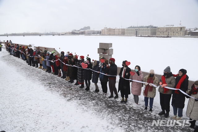 [상트페테르부르크=AP/뉴시스] 2월14일 러시아 상트페테르부르크에서 러시아 야권 지도자 알렉세이 나발니와 그의 아내 율리아를 지지하는 여성들이 인간 띠를 형성하고 나발니의 석방을 촉구하는 시위를 벌이고 있다. 2021.02.15.