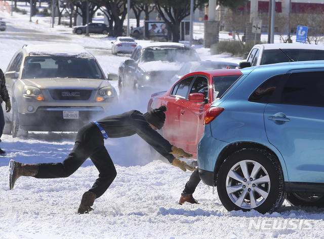 [웨이코=AP/뉴시스] 15일(현지시간) 미국 텍사스주 웨이코의 눈 쌓인 도로에서 사람들이 차를 밀고 있다. 2021.02.16.