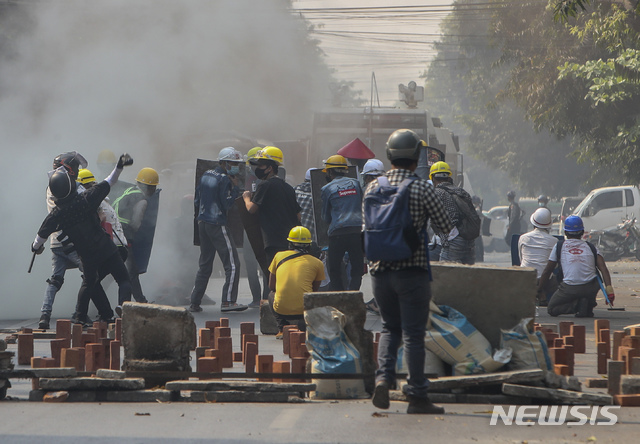 [만달레이=AP/뉴시스]3일 미얀마 만달레이에서 군부 쿠데타 반대 시위대가 임시 구조물을 방패 삼아 경찰이 발사한 최루탄에 맞서고 있다. 2021.03.03. 