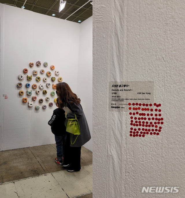 [서울=뉴시스] 박현주 미술전문 기자=2021 화랑미술제에 참여한 학고재갤러리에서 전시한 김재용의 도넛은 '빨간딱지' 풍년이어서 이번 행사에서 주목받았다. '팔렸다'는 빨간딱지가 82개나 붙어있는 이 도넛 조각은 밀가루가 아닌 도자로 만들어져 한 개에 105만원에 판매했다. 