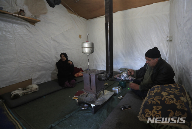 [AP/뉴시스] 2021년 3월 레바논 동부 베카 인근 시리아 난민촌의 한 텐트 내부. 10년 전 탈주한 가족의 남편이 뜨거운 차를 마시고 있다