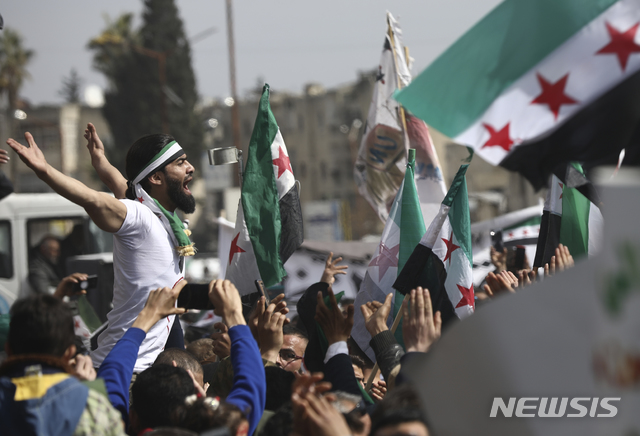 [이들리브=AP/뉴시스]시리아 반정부 시위대 수천 명이 15일(현지시간) 민주화 시위 10주년을 맞아 시리아 이들리브에서 혁명기를 들고 구호를 외치고 있다. 2011년 3월 15일 '아랍의 봄'으로 불리는 민주화 시위는 내전으로 번져 10년째 이어지고 있으며 그간 약 39만 명이 목숨을 잃었다. 2021.03.16.