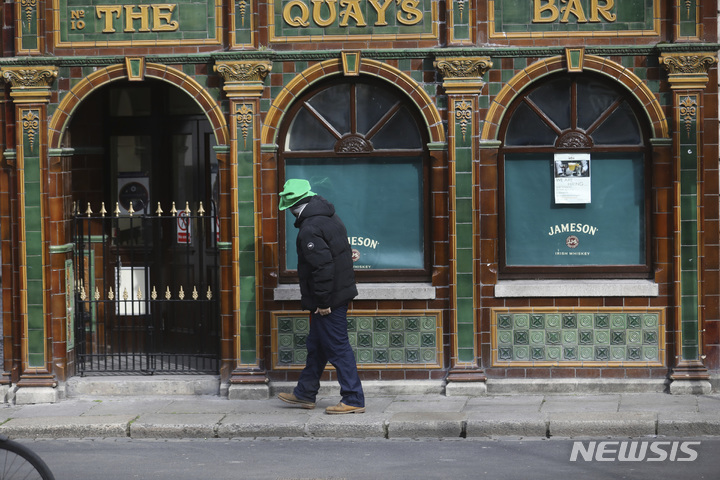 [더블린=AP/뉴시스] 지난 3월17일(현지시간)자 사진에서 한 남성이 아일랜드 수도 더블린의 문 닫힌 술집 앞을 지나고 있다. 2021.12.20.