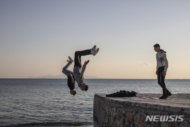 [아테네=AP/뉴시스]1일(현지시간) 그리스 아테네 외곽 알리모스 해변에서 놀던 시리아 출신 청소년들이 공중돌기를 하고 있다. 2021.04.02.