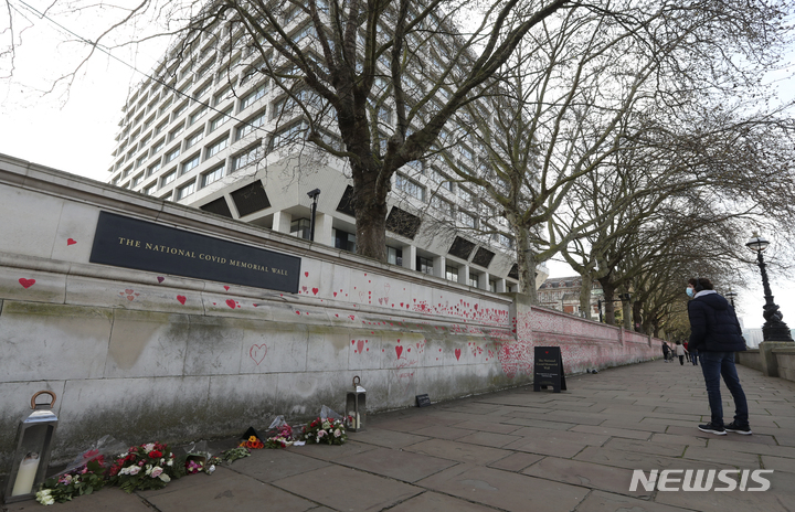 [런던=AP/뉴시스]지난 4월4일(현지시간)자 사진에서 한 남성이 영국 런던 의사당 맞은편 세인트 토머스 병원 앞에 있는 '코로나19 희생자 추모의 벽'을 바라보고 있다. 2021.11.09.