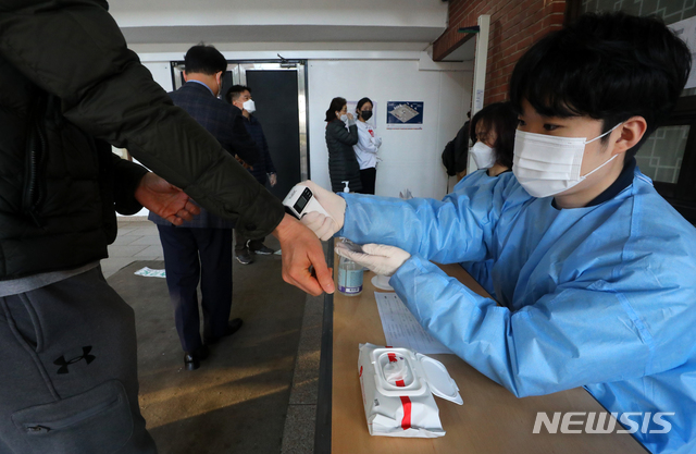 [서울=뉴시스]배훈식 기자 = 2021 재·보궐선거 투표일인 7일 오전 서울 강남구 단국대학교 사범대학 부속중학교 체육관에 마련된 대치1동 제1투표소에서 선거사무원이 투표소를 찾은 시민의 체온을 측정하고 있다. 2021.04.07. dahora83@newsis.com