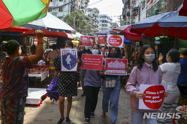 [양곤=AP/뉴시스]7일(현지시간) 미얀마 양곤에서 반 쿠데타 시위대가 "중국은 좋은 이웃이 아냐" "우리는 멈추지 않는다" 등이 쓰인 팻말을 들고 상인들의 환영을 받으며 시장을 행진하고 있다. 2021.04.07