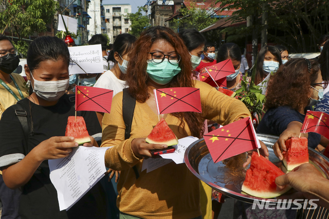 [양곤=AP/뉴시스]13일 미얀마 양곤에서 반 쿠데타 시위대가 훼손한 중국 국기를 수박 조각에 꽂아 들고 있다. 시위대는 미얀마 시장 내 일부 국내 상품의 가격에 영향을 끼친 중국과의 교역을 중단할 것을 촉구하고 있다. 2021.04.13.