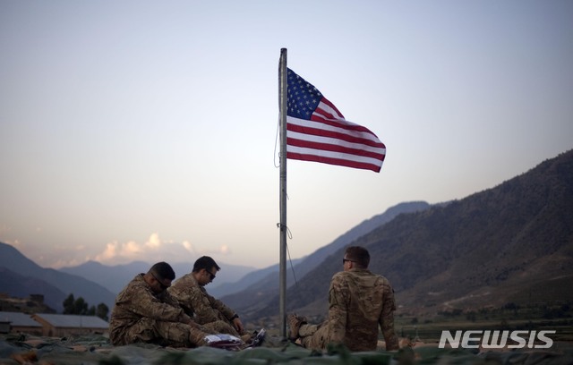 [쿠나르=AP/뉴시스]2011년 9월11일(현지시간)자 사진에서 미군들이 아프가니스탄 쿠나르주(州)에 있는 전방 작전 기지 보스틱에서 9.11테러 10주년을 기념하기 위해 게양한 미국 국기 아래에 둘러 앉아 있다. 2021.06.25.