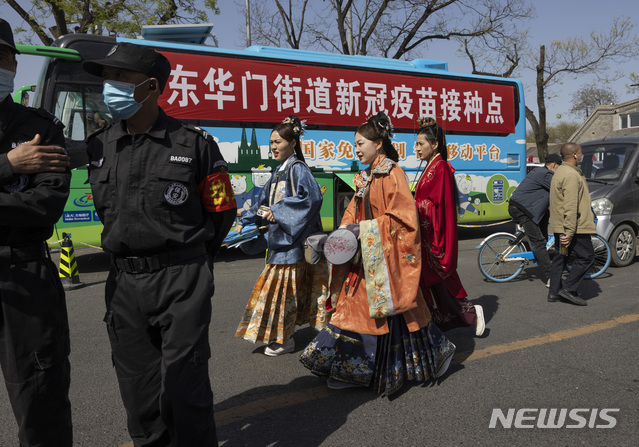 [베이징=AP/뉴시스]지난 14일 중국 베이징의 자금성 주변에서 전통 의상을 입은 주민들이 무료로 코로나19 백신 접종을 제공하는 버스 앞을 지나고 있다. 2021.04.16.