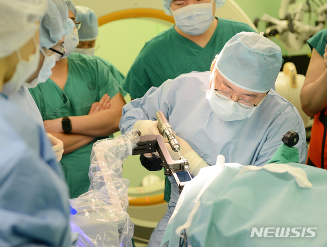[서울=뉴시스]장원석 교수가 국내 최초로 개발된 뇌수술 보조 로봇장비 카이메로를 이용해 환자의 뇌심부에 전극을 삽입하고 있다. 카이메로를 이용한 뇌전증 수술은 약 2~3mm의 작은 구멍으로 전극을 삽입할 수 있어 수술시간도 짧고, 부작용이나 수술 후 통증도 줄일 수 있다. (사진= 세브란스병원 제공)2021.04.22