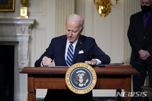 [AP/뉴시스] 조 바이든 미 대통령이 취임 직후인 1월27일 백악관에서 기후변화에 관한 행정명령에 사인하고 있다