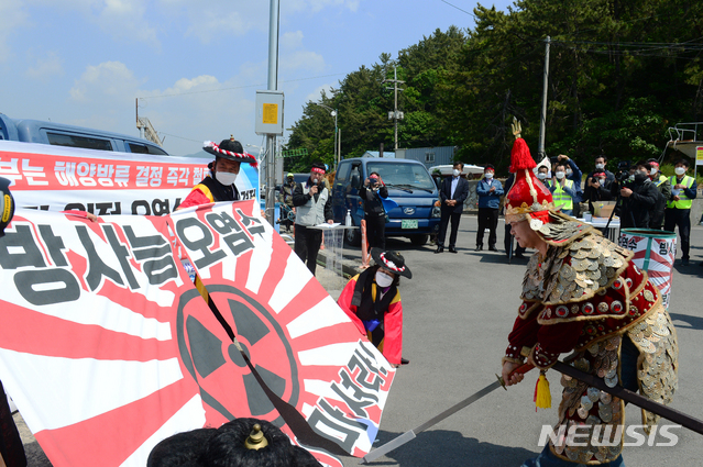 [남해=뉴시스]차용현 기자 = 30일 오전 경남 남해군 미조항 인근 방파제에서 열린 일본 후쿠시마 원전 오염수 해양 방류 규탄대회에서 이순신 장군으로 분장한 한 어민이 욱일기를 칼로 자르고 있다. 2021.04.30. con@newsis.com