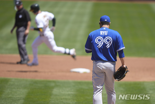 Toronto Blue Jays pitcher Hyun Jin Ryu (99) stands on the mound as Oakland Athletics&#039; Mark Canha, second from left, rounds the bases after hitting a solo home run during the first inning of a baseball game in Oakland, Calif., on Thursday, May 6, 2021. (AP Photo/Tony Avelar)