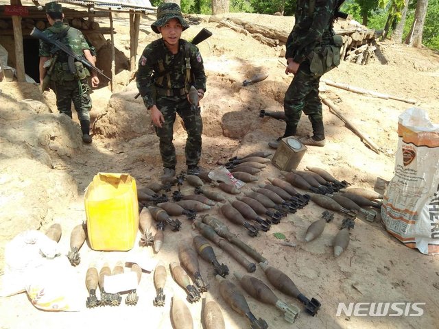 [무트로(미얀마)=AP/뉴시스]7일(현지시간) 미얀마 카렌주 무트로 지역에서 카렌 민족해방군의 한 병사가 미얀마군 초소에서 발견한 박격포탄 무더기 옆에서 박격포탄을 들고 있다. 반군 고위 간부는 카렌족 게릴라가 미얀마 군부대 전초기지를 점령해 불태웠다고 밝혔다. 2021.05.07. 