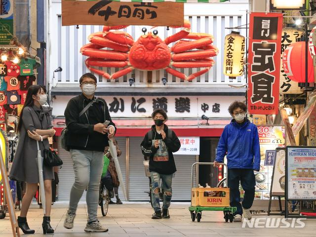[오사카(일본)=AP/뉴시스]지난 7일 일본 오사카에서 코로나19 감염을 우려, 마스크를 착용한 시민들이 거리를 걷고 있다. 일본에서 9일 오후 8시30분 현재 6487명이 코로나19에 새로 감염된 것으로 확인됐다고 NHK 방송이 보도했다. 이로써 일본은 사흘 연속 하루 신규 감염자 수가 6000명을 넘어섰다. 2021.5.9