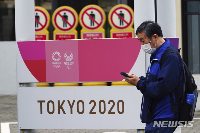 [도쿄=AP/뉴시스]이달 11일 일본 도쿄에서 코로나19 확산 방지를 위해 마스크를 쓴 한 남성이 2020 도쿄올림픽·장애인올림픽 홍보물 앞을 지나가고 있다. 2021.05.14.
