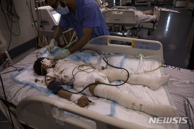 [가자지구=AP/뉴시스] 지난 13일(현지시간) 팔레스타인 가자 지구의 시파 병원 중환자실에서 한 의료인이 전날 이스라엘의 공습으로 부상한 소녀를 치료하고 있다. 지난 몇 주간 급증하는 코로나19로 어려움을 겪던 열악한 의료 시스템의 의료진은 이제 이스라엘 공습에 따른 폭발과 파편에 의한 부상, 절단 등의 환자를 돌봐야 하는 이중고를 겪고 있다. 2021.05.14.