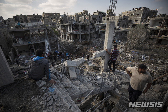 [가자지구=AP/뉴시스]14일(현지시간) 팔레스타인 가자 지구 북부의 베이트 하노운 마을에서 주민들이 지난밤 이스라엘의 공습으로 파괴된 집들을 바라보고 있다. 2021.05.14.