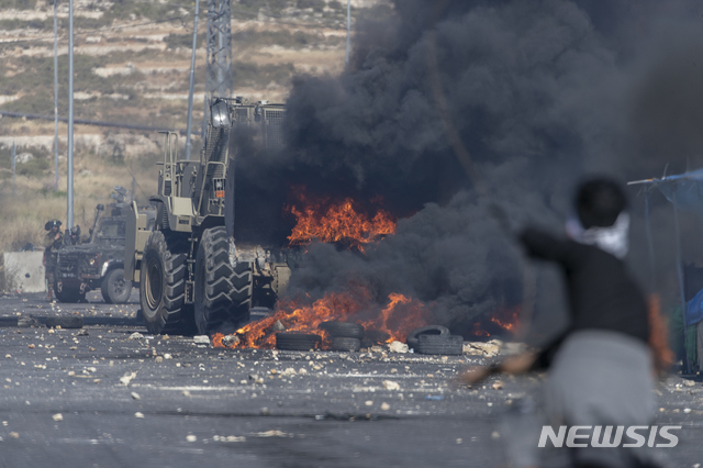 [라말라=AP/뉴시스] 14일(현지시간) 요르단강 서안지구 라말라에서 이스라엘군 불도저가 팔레스타인 시위대가 길을 막기 위해 던진 불붙은 타이어를 처리하고 있다. 2021.05.15. 