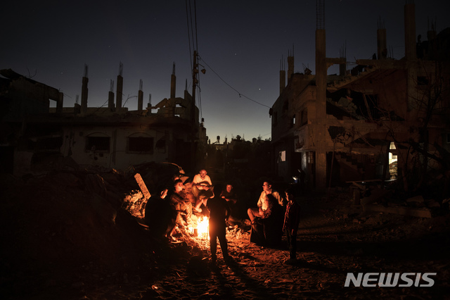 [가자지구=AP/뉴시스]26일(현지시간) 팔레스타인 가자지구 북부 베이트 하노운 마을에서 팔레스타인 주민들이 최근 이스라엘의 공습으로 파괴된 집 주변에 모여 앉아 모닥불을 피우고 밤을 보내고 있다. 2021.05.27.