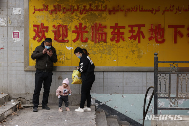 [아커쑤=AP/뉴시스] 3월18일(현지시간) 중국 신장위구르 자치구의 아커쑤에 있는 지하 쇼핑가 입구에 가족들이 서있다. 2021.06.24.
