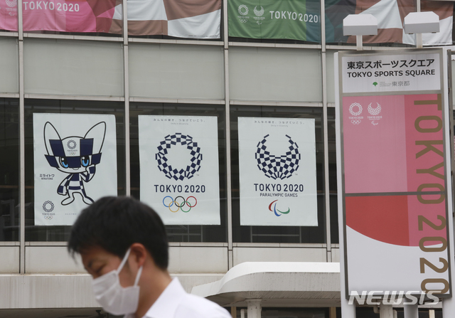 [도쿄(일본)=AP/뉴시스]지난 7일 도쿄올림픽 홍보 포스터가 내걸린 도쿄 거리를 마스크를 착용한 시민이 지나가고 있다. 2021.06.18.